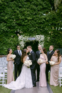 Bride and groom share a kiss in front of their chuppah, surrounded by their wedding party at the Four Seasons Beverly Hills.