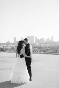 Black and white photo of bride and groom on the rooftop of the Four Seasons Beverly Hills with DTLA in the background.