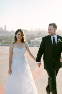 Bride and groom walk and hold hands while taking sunset photos on the helipad at the Four Seasons Beverly Hills.