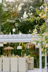 White and yellow striped upholstered chairs are the perfect compliment to this beautifully designed outdoor reception for an intimate spring microwedding with cheerful yellow decor.