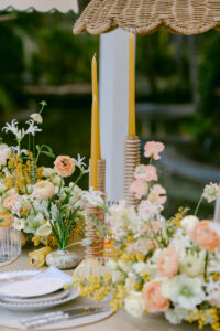 A table setting adorned with yellow and white flowers alongside flickering candles, creating an inviting atmosphere.