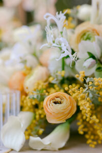 A spring themed wedding reception table adorned with a bouquet of white and yellow flowers, creating a vibrant and fresh centerpiece.