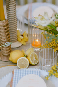 Vibrant yellow themed wedding tablescape featuring yellow florals, textured wooden candle holders, yellow candles and lemons for the perfect Spring wedding reception.