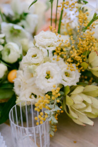 A table adorned with white and yellow flowers, complementing a wedding cake for a yellow-themed spring wedding.