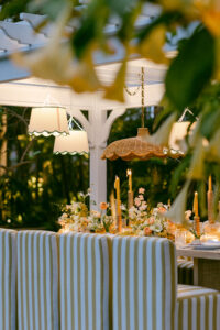 A candlelit dining table surrounded by white and yellow striped chairs, framed by yellow florals, creating a vibrant and inviting atmosphere.