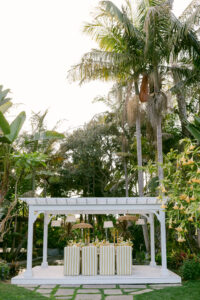 A white gazebo surrounded by yellow and white striped chairs, set in a serene outdoor environment for a micro-wedding reception.