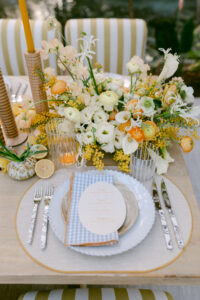 A beautifully arranged table setting featuring vibrant yellow and white flowers in elegant vases.