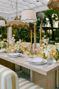 An intimate dinner party table elegantly set, surrounded by yellow and white striped chairs, ready for guests.