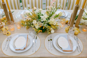A beautifully arranged table setting featuring vibrant yellow and white flowers in elegant vases for a spring wedding.
