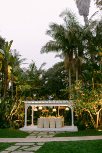 A gazebo surrounded by a vibrant garden, set for a yellow-themed spring wedding celebration.