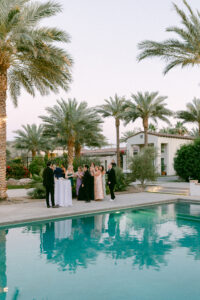 Poolside cocktail hour with the palm trees reflecting off the water at one of the best wedding venues in Southern California, Cache Estate.
