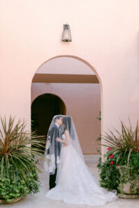 Bride and Groom share a kiss under her veil, under architectural arches at Hotel Bel-Air Wedding